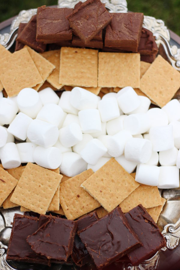 An elegant silver tray holds marshmallows, graham crackers, and large slices of fudge ready to be assembled into smores.